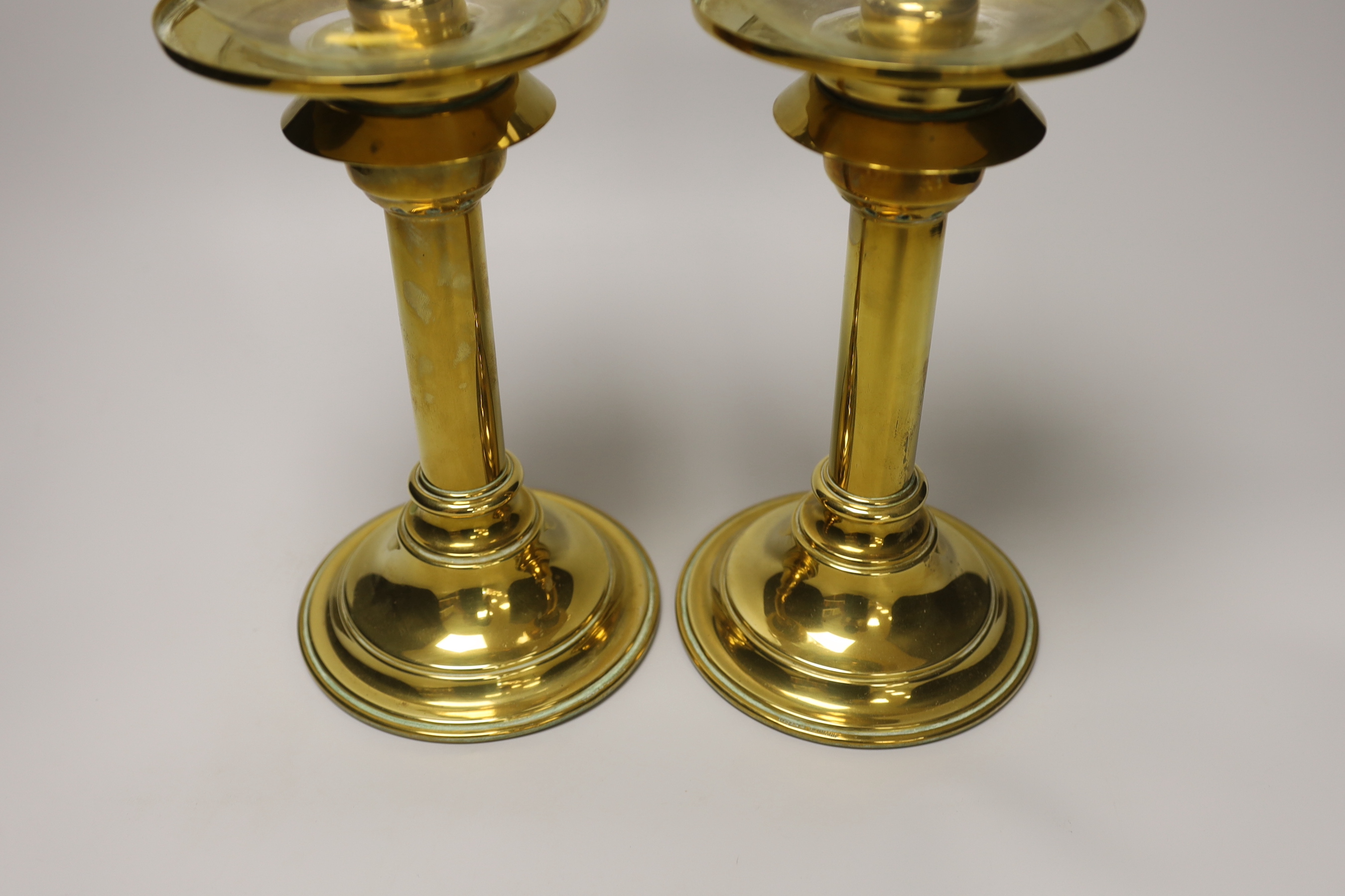 A pair of brass candlesticks with spring loading actions and storm shades and a Victorian cast brass adjustable reading stand with pierced and embossed decoration, the largest each 37cm high
